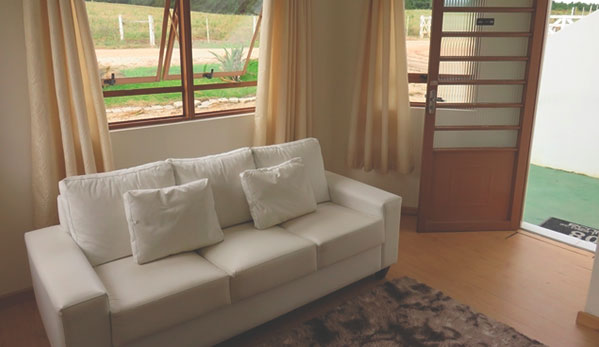 Ambiente interno com sofá e vista para o jardim